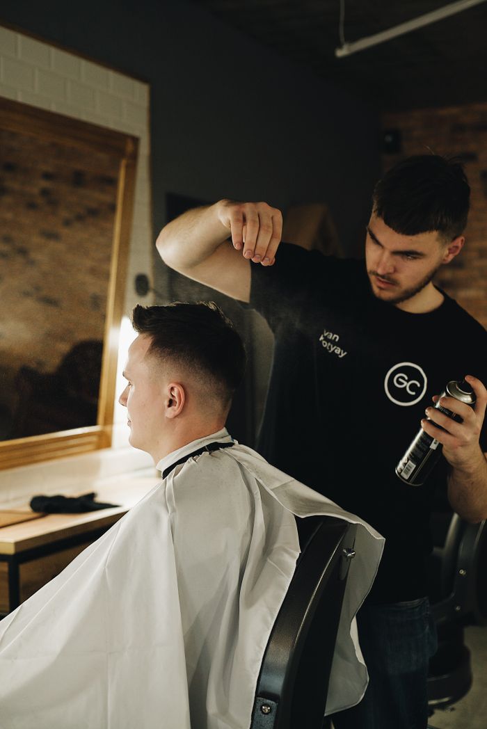 Barber styling client's hair in a contemporary shop, showcasing grooming and care.
